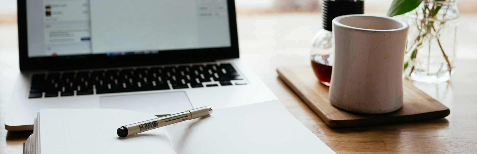 A desk showing a laptop and a notepad 